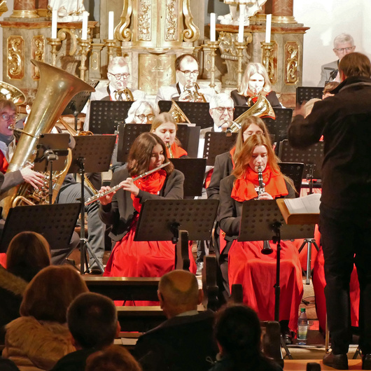 Blick vom Kirchenraum auf einen Teil der Musikkapelle. Der Dirigent steht mit dem Rücken zur Kamera.