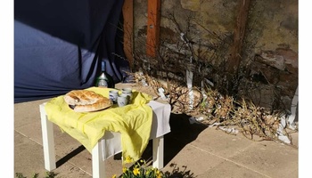 Ein kleiner Tisch, auf dem ein geteiltes Fladenbrot und drei Becher stehen als Smybol für den Ostermontag.