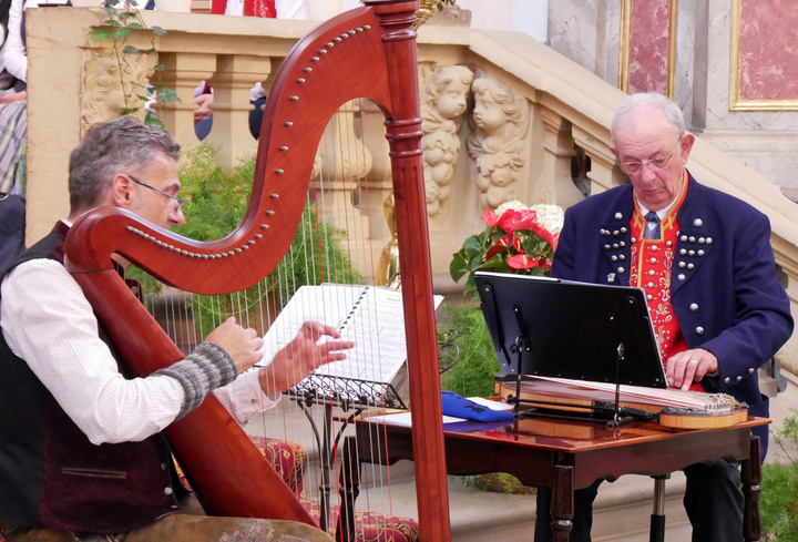 Zwei Männer spielen Harfe und Zither.
