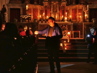 Ein Mann gibt in der Kirche kleine Kerzen weiter.