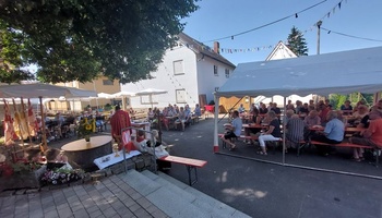 Das Bild zeigt den Festplatz mit Menschen auf Bierbänken in Festzelten. In der Mitte steht der Altar für den Gottesdienst.