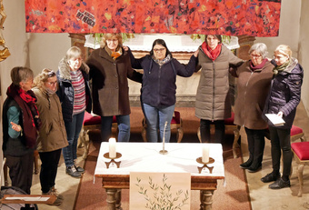 Acht Frauen stehen um den Altar in der Hausener Kirche. Die Hände haben sie sich auf die Schultern gelegt.