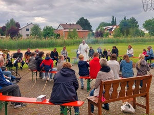 Blick auf eine Runde um ein Lagerfeuer auf dem Bolzplatz