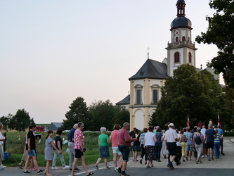 Ein Ausschnitt mit Prozessionsteilnehmenden. Im Hintergrund sieht man die Wallfahrtskirche.