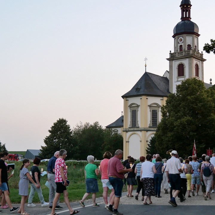 Ein Ausschnitt mit Prozessionsteilnehmenden. Im Hintergrund sieht man die Wallfahrtskirche.