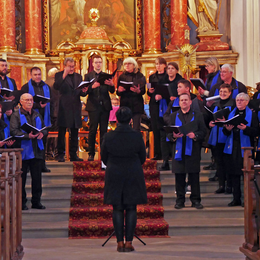 Auf den Altarstufen der Kirche steht ein Chor und singt