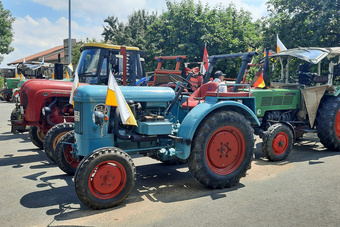 Mehrer geschmücke Oldtimer-Traktoren stehen nebeneinander auf dem Parkplatz des Hausener Sportvereins.