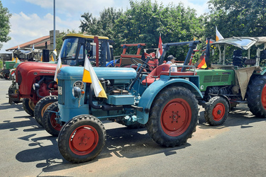 Mehrer geschmücke Oldtimer-Traktoren stehen nebeneinander auf dem Parkplatz des Hausener Sportvereins.
