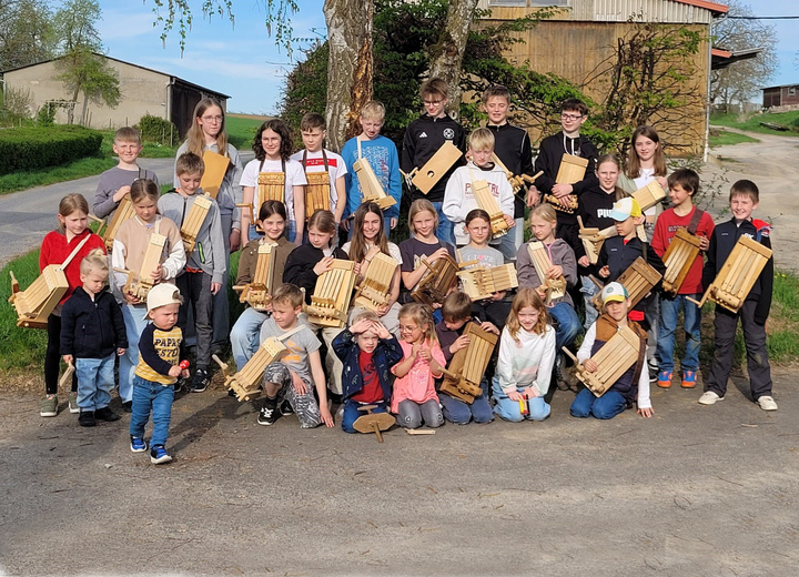 Das ist ein Gruppenbild vor einem Baum mit vielen Kindern.