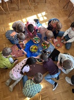 Blick von oben auf mehrere Kinder, die auf dem Boden sitzen und basteln.